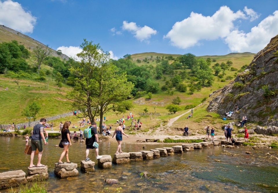 Tourists crossing River Dove on stepping stones in Dovedale Derbyshire peak district national park England UK GB EU Europe