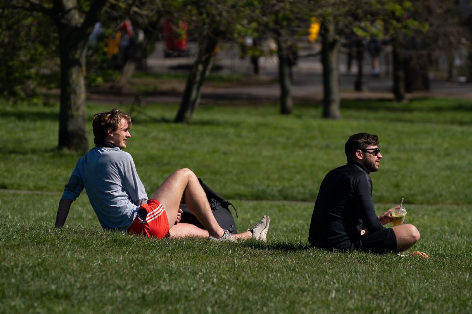  Two men relax in the sun on Primrose Hill, London