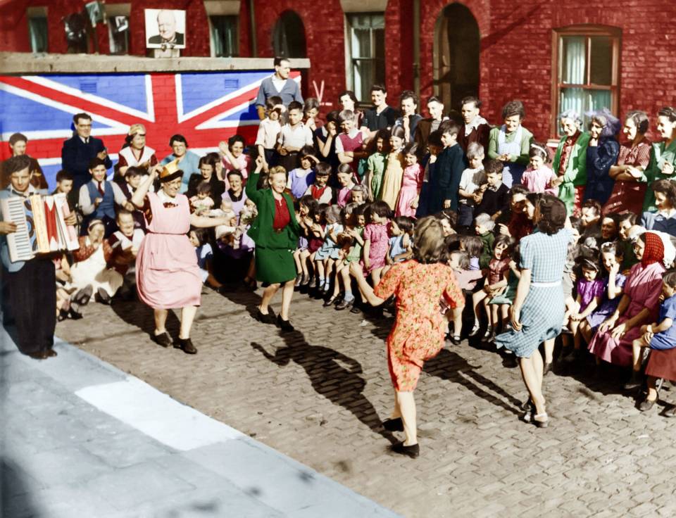 Woman dancing in celebration as children look on in Chorlton-on-Medlock(now Manchester)