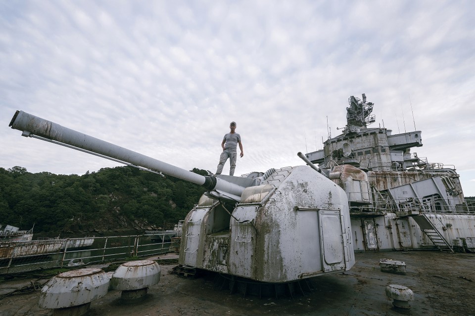  One of the party stand on top of a ship's gun turret