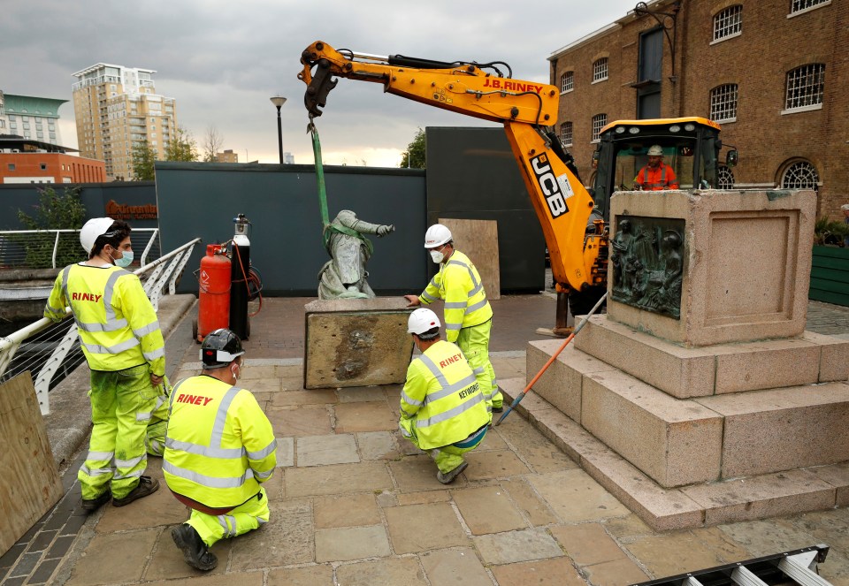 Workers can be seen removing the statue from its plinth after a similar one was toppled by protesters in Bristol over the weekend