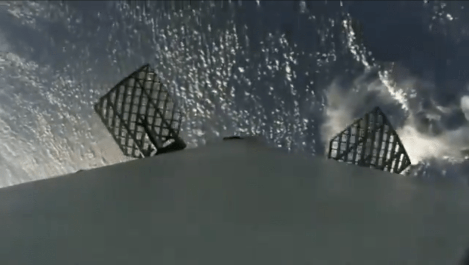 A Falcon 9 rocket booster with a view of Earth below as the machine begins its descent back to our planet following the launch of a satellite