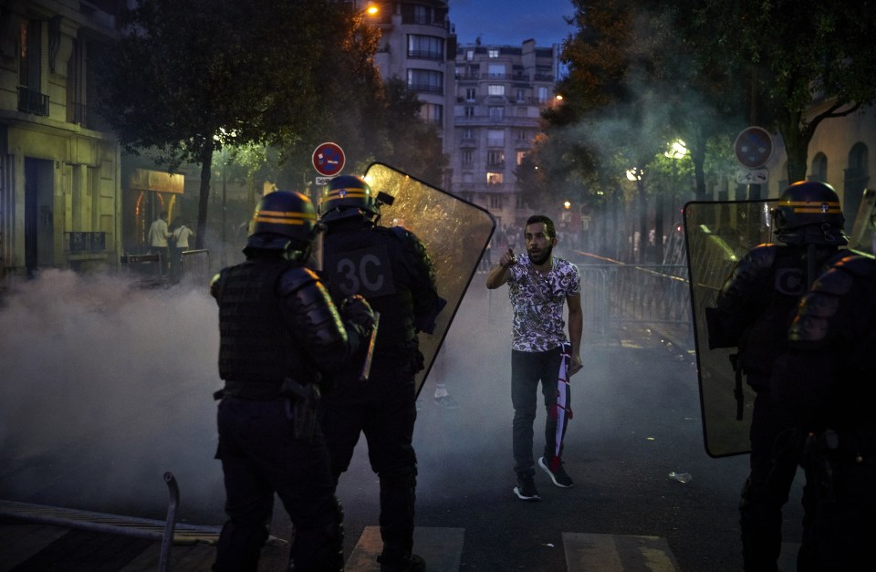A man stands in front of a row of riot police