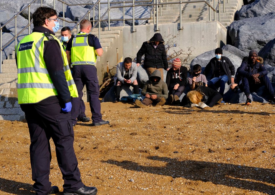 Exhausted refugees sit in the sand near Dover