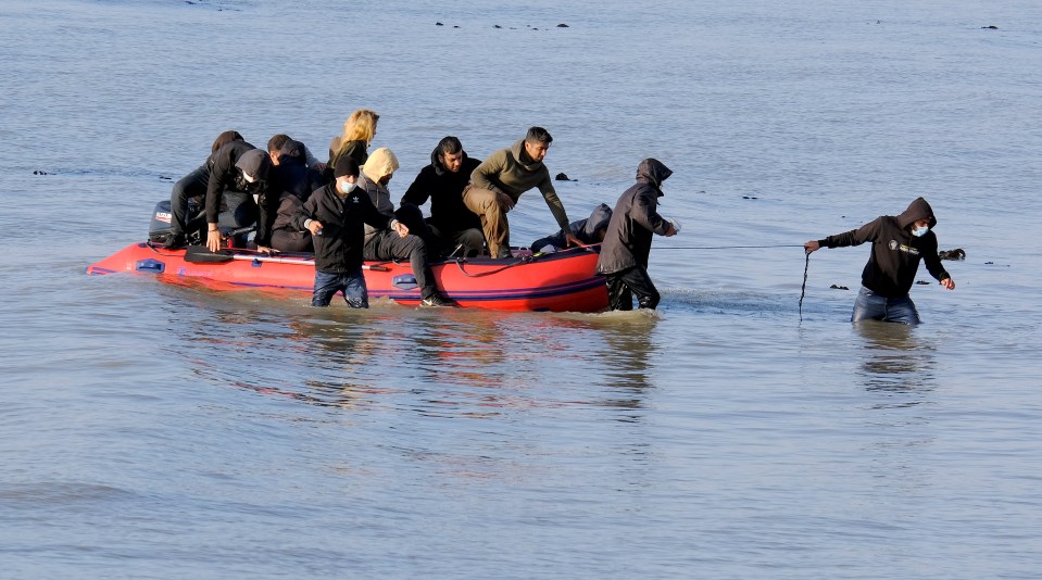 A man pulls the boat to the shore after making the journey from France