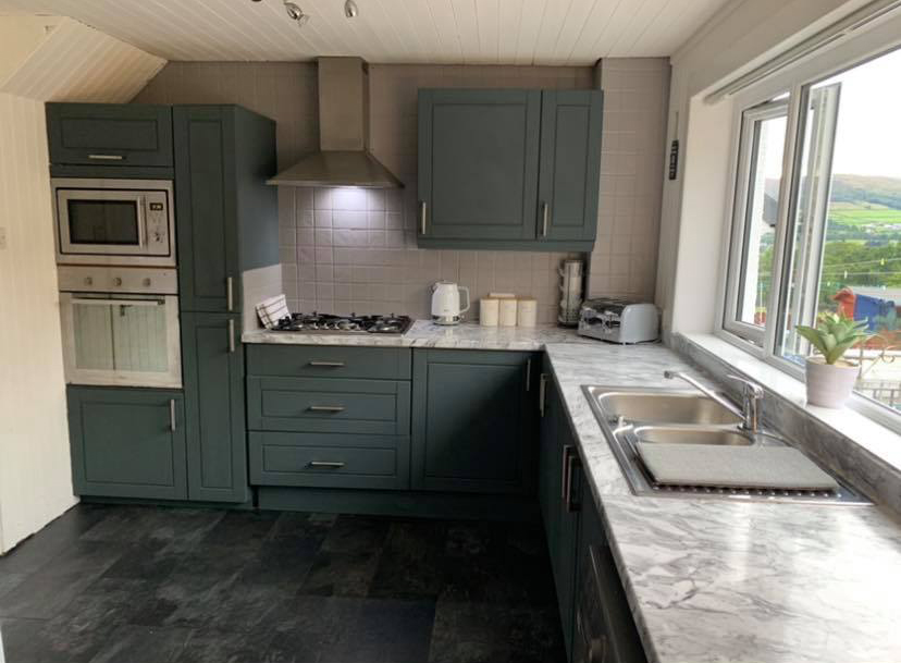 The new kitchen is a modern shade of teal with chic marble-effect worktops
