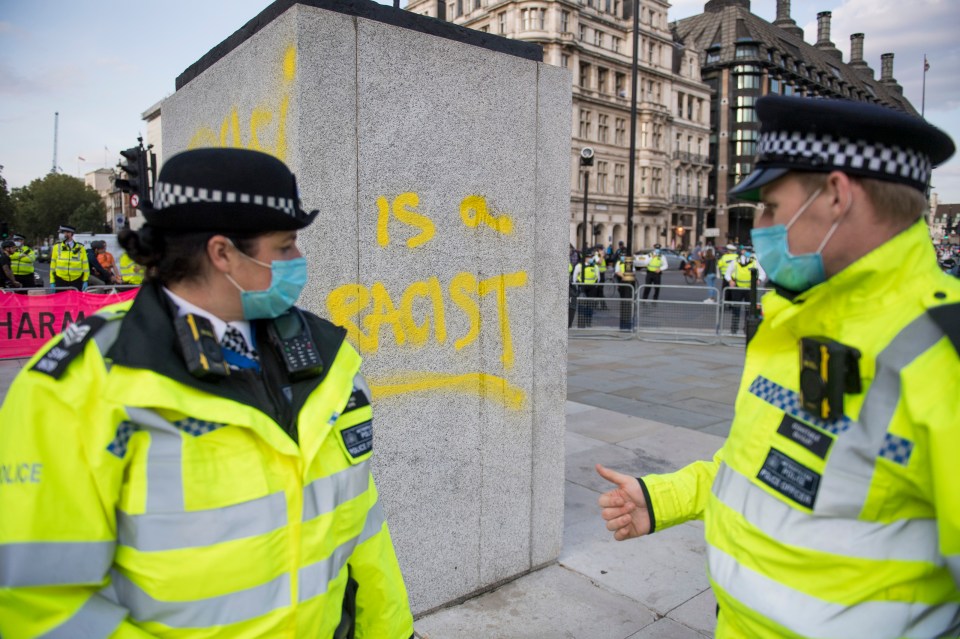 Two police stand next to the newly- defaced statue