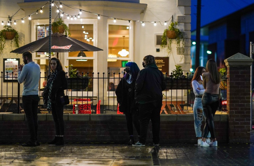 Drinkers in Tyneside, which won't yet be faced with stricter measures, queue for a pub at a distance from each other