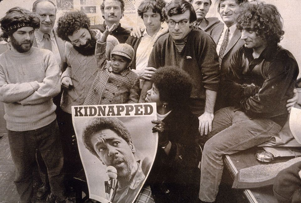 Chicago Seven members posing with a poster of Seale reading 'Kidnapped' after he was severed from the trial