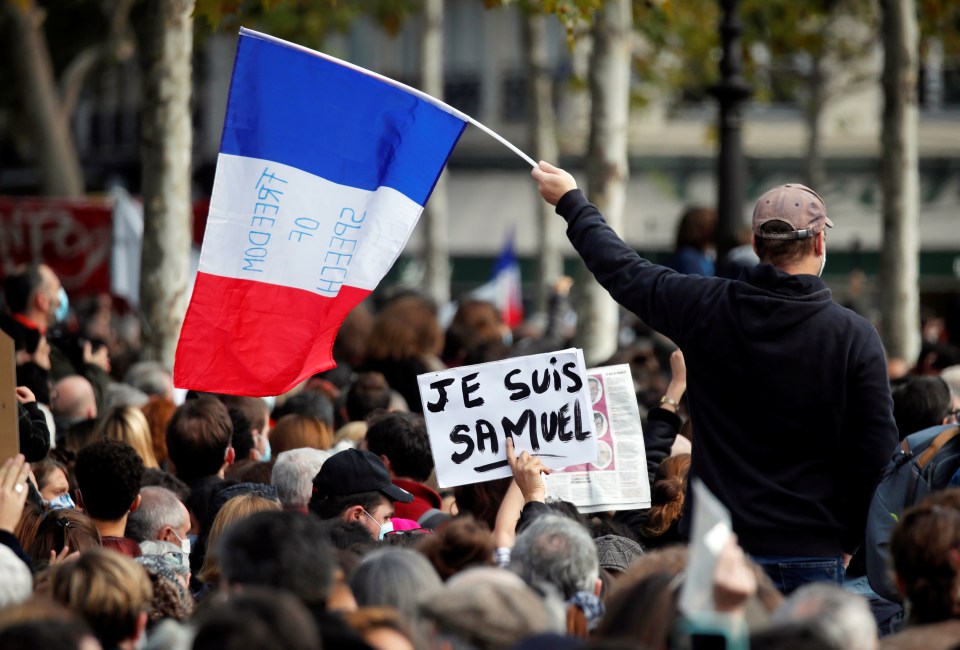 A man waves a French flags with the words 'freedom of speech' 