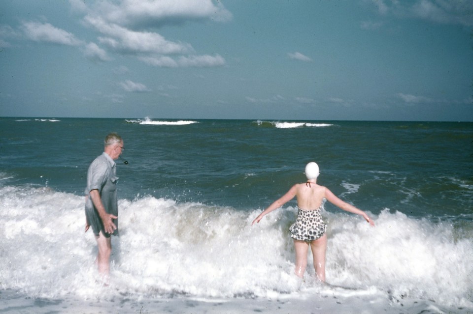 Two beach-goers enjoy a dip in the water as waves crash onto the shore