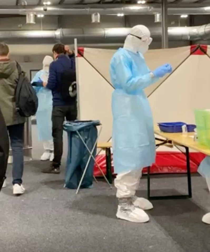 A nurse in a hazmat suit screening passengers 