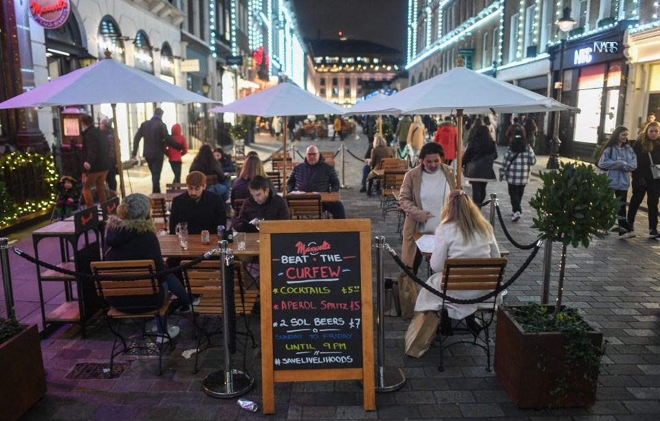 People sit outside drinking at a bar near Covent Garden in London 