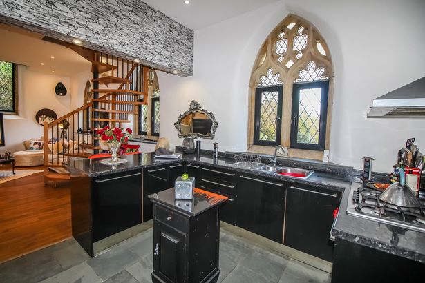 The sleek kitchen has black marble-top counters with the spiral staircase leading to the upstairs just behind 