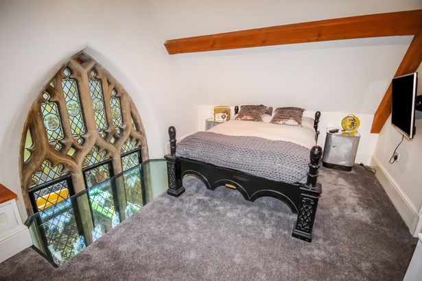 A bedroom overlooking a glass stained window resides inside