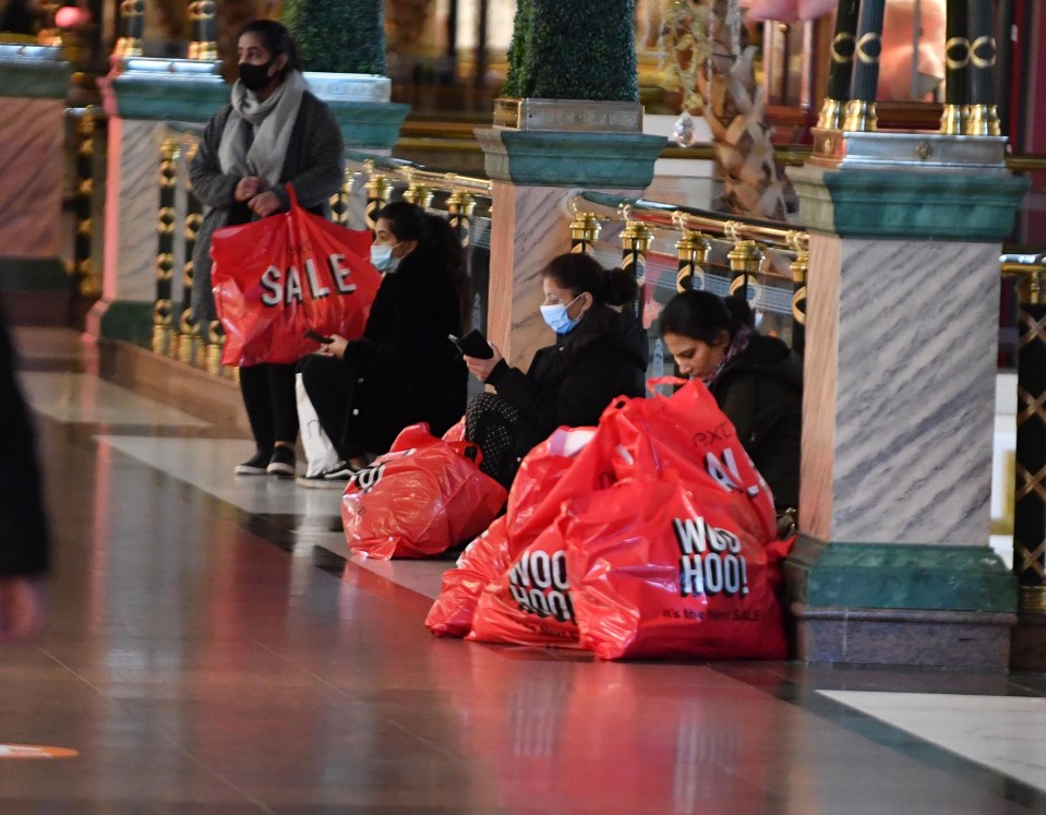 Shoppers sit surrounded by bulging Next bags in Manchester 
