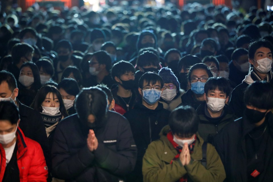 Crowds of people wear masks as they pray at the Kanda Myojin shrine on the first day of the new year in Tokyo, Japan 