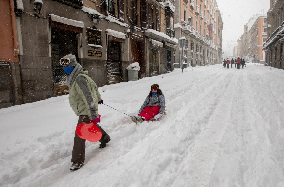  A woman pulls a girl on a sledge through the streets of Madrid
