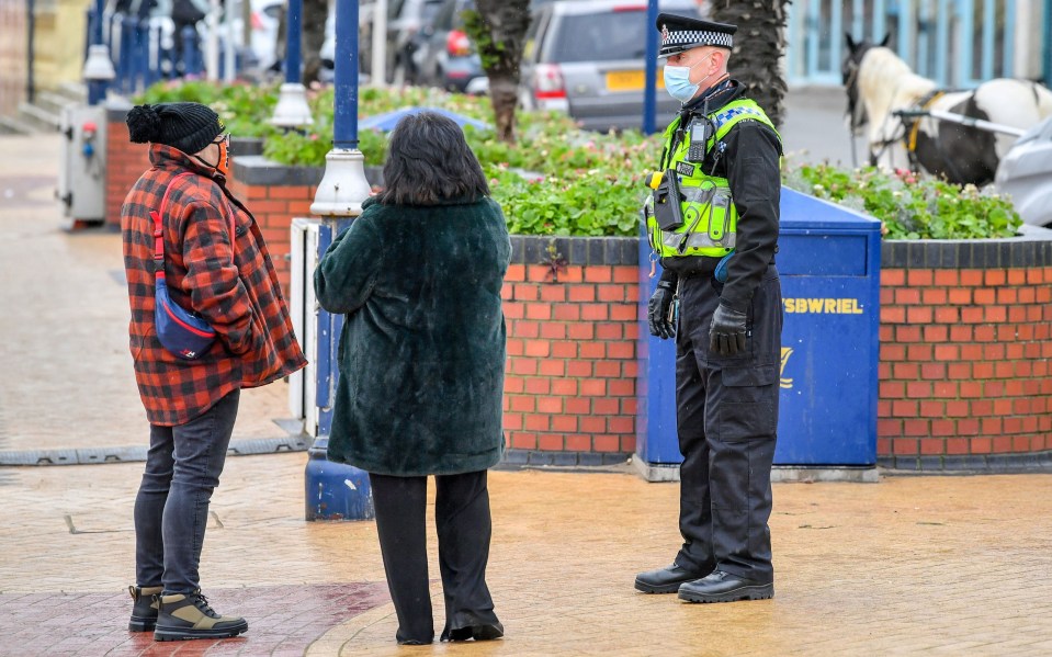 A policeman talks to members of the public in Barry Island, Wales