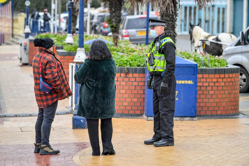 A policeman talks to members of the public in Barry Island, Wales