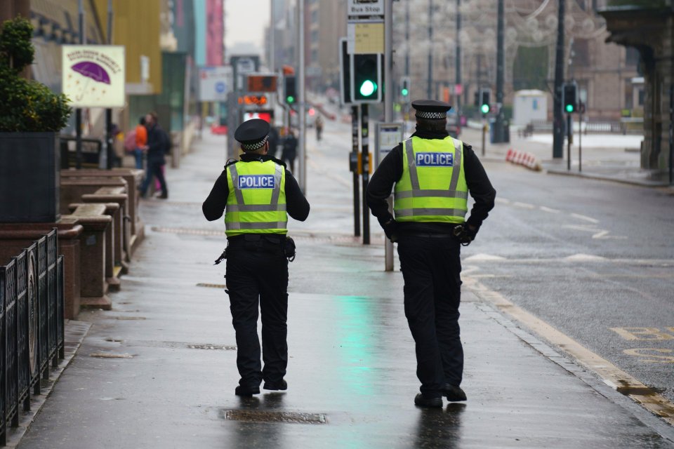 Two police officers patrol an empty street in Glasgow this morning