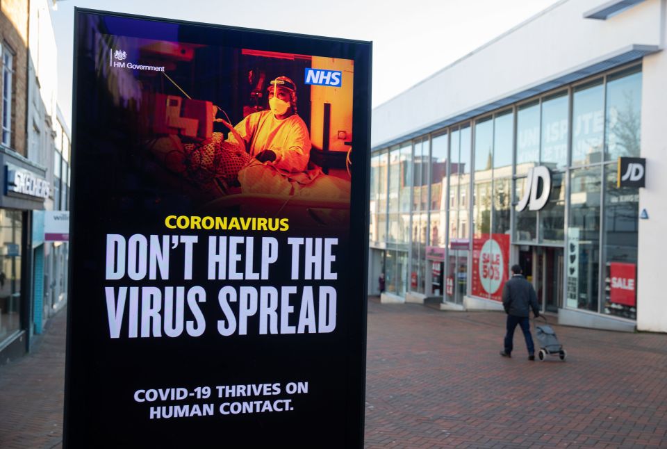 A person passes a 'don't help the virus spread' government coronavirus sign in Bournemouth