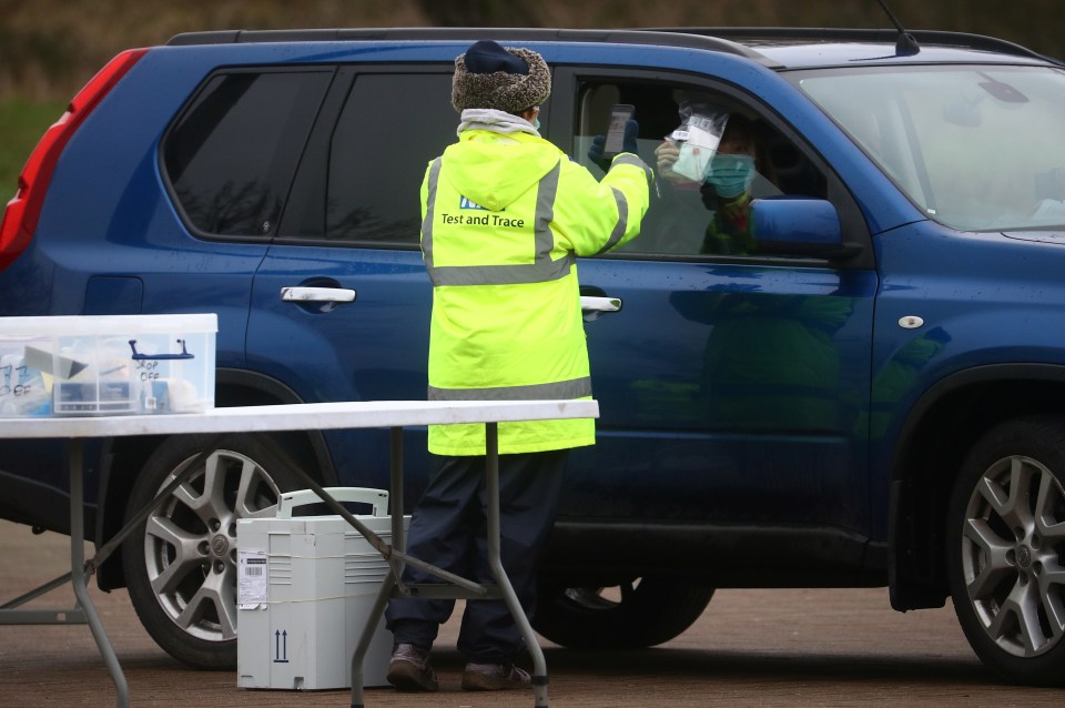 A worker collects a swab from a car window at a test centre in Goldsworth Park, Surrey, where two cases of the South African strain were detected