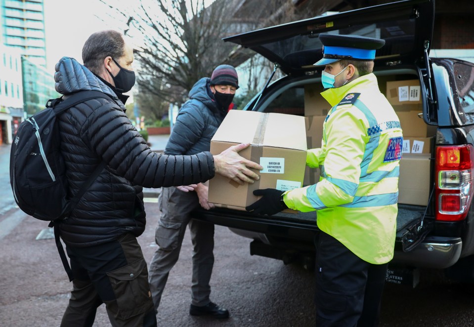 Volunteers are seen unloading boxes of test kits at a site in Woking this morning 