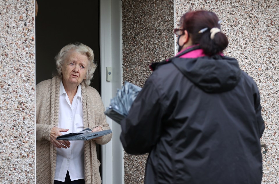 Volunteers hand out the Covid-19 home test kit to a resident in Goldsworth and St Johns
