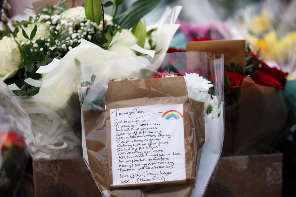 A handwritten note left with flowers is seen near Captain Sir Tom Moore's house