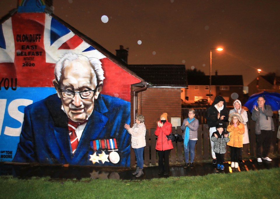 Local residents join a national clap beside a mural of Captain Sir Tom Moore in East Belfast