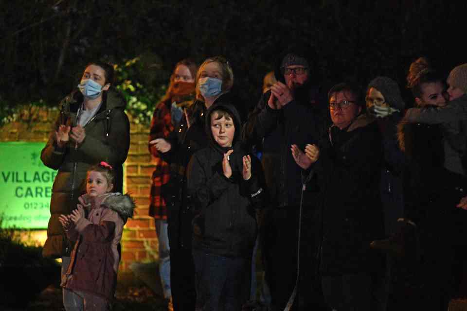 Locals join Captain Sir Tom's daughter Hannah Ingram-Moore, with her children Benjie and Georgia and husband Colin Ingram outside their house to pay tribute
