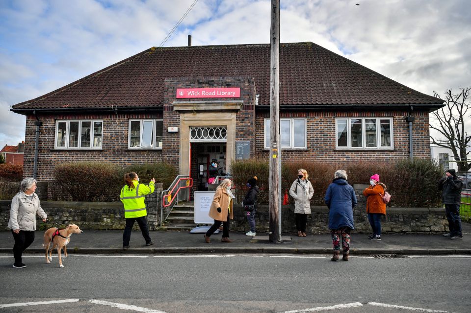 People wait in line for a coronavirus test at a surge test centre set up in a library in the Bristol area