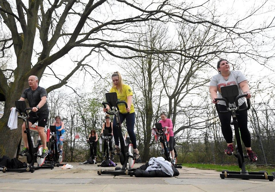 Cyclists train in an outdoor group spinning class at Hampton Lido, London