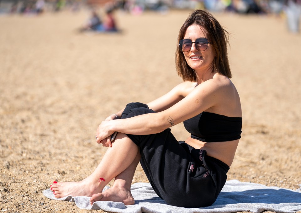 A woman soaks up the sun on Southend beach, Essex