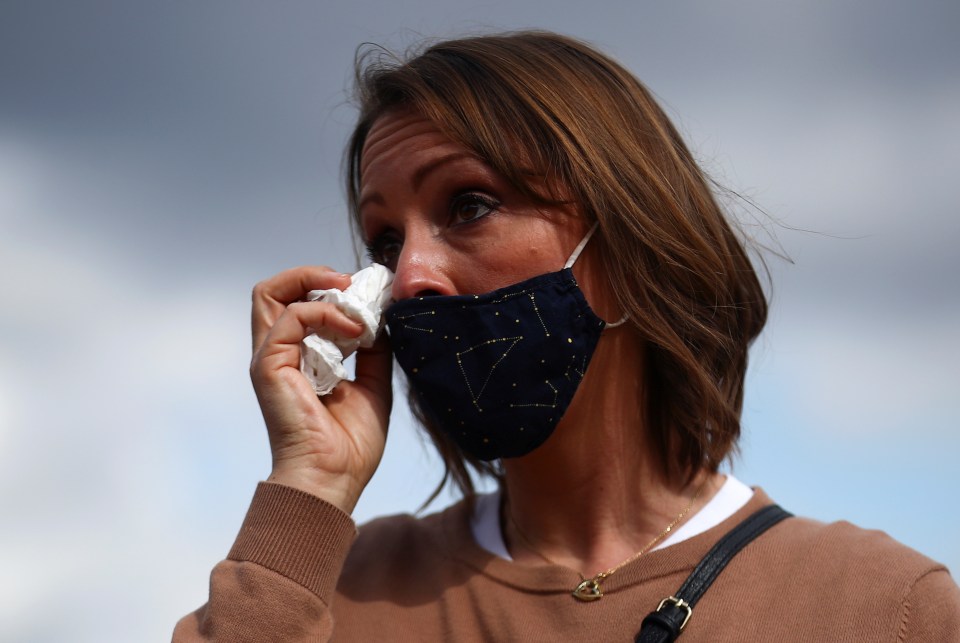 A woman wipes away a tear from her eye