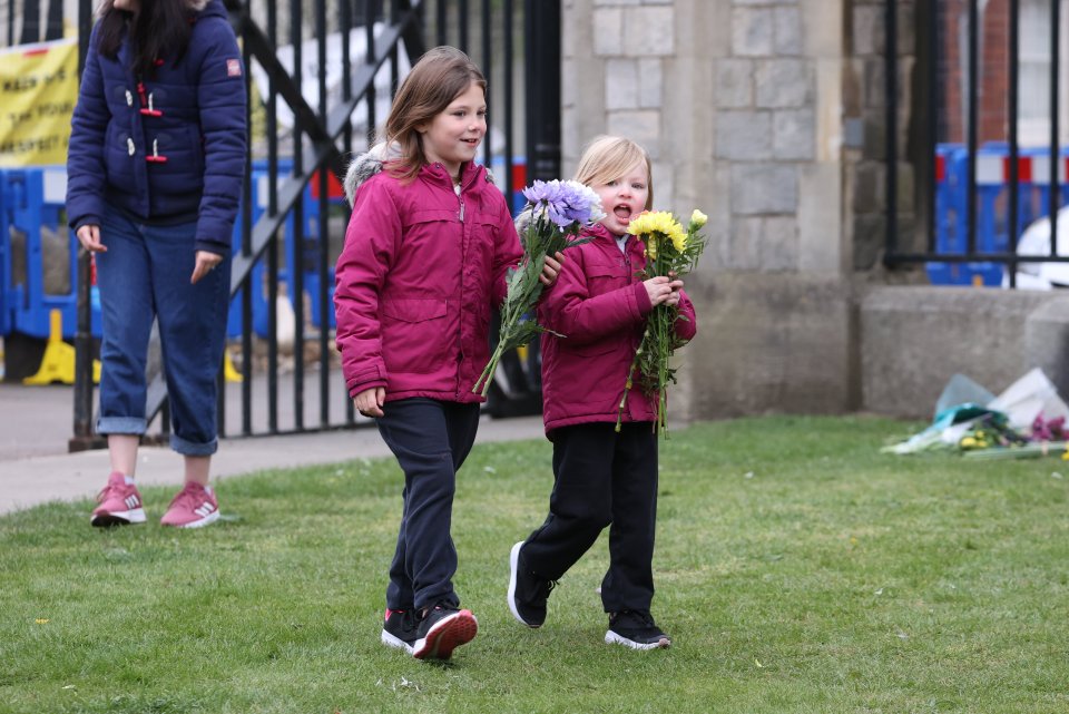 Two children laying flowers at Windsor Castle the day after Prince Philip died 'peacefully' at the age of 99