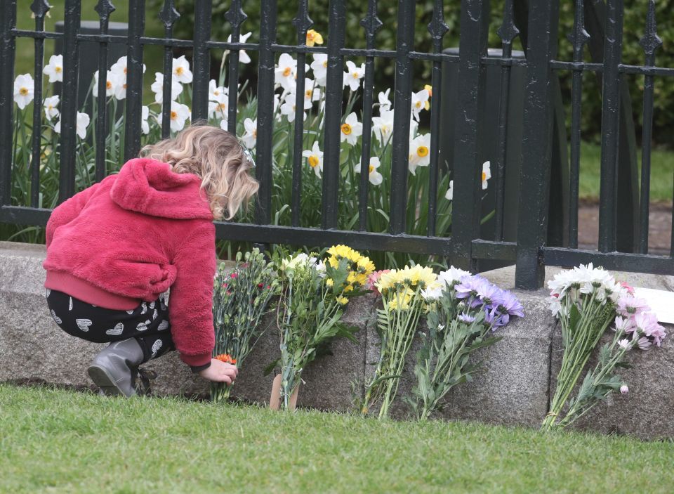 A young girl placing flowers outside Windsor Castle, where the Prince died yesterday