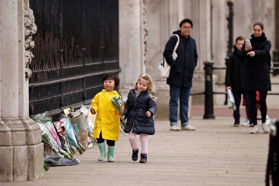 Young children carry flowers to lay in Prince Philip's memory outside Buckingham Palace