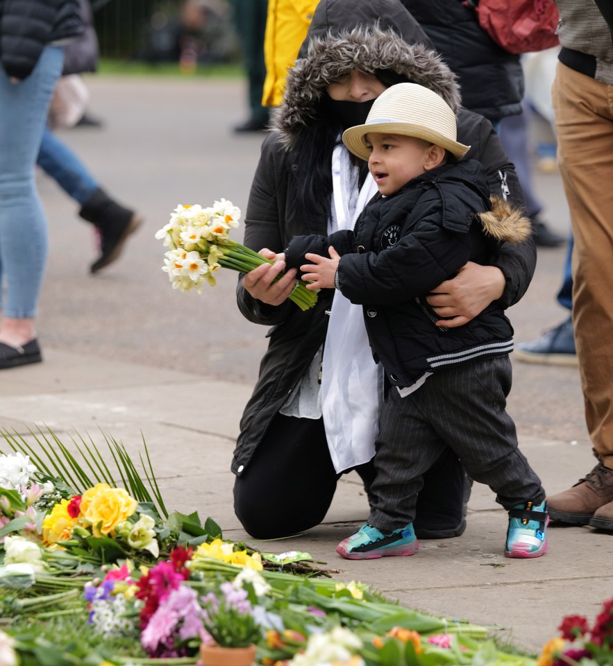 A mother and child put down flowers in the Prince's memory