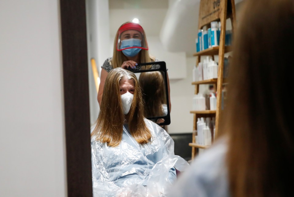 Kelly Boad, owner of The Hair & Beauty Gallery, holds a mirror after giving Sue Butcher a haircut after reopening last night