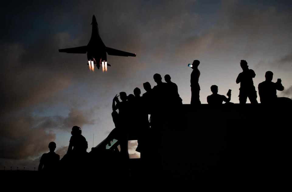9th Expeditionary Bomb Squadron B-1B Lancer mechanics take selfies as a B-1B flies overhead at Andersen Air Force Base, Guam