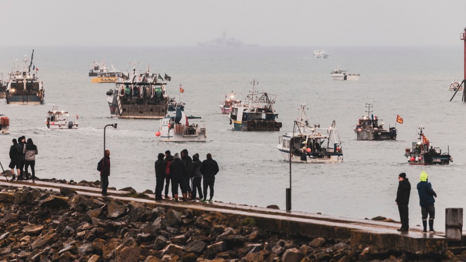 Onlookers watch from shore as the French fleet patrols the waters close to the island