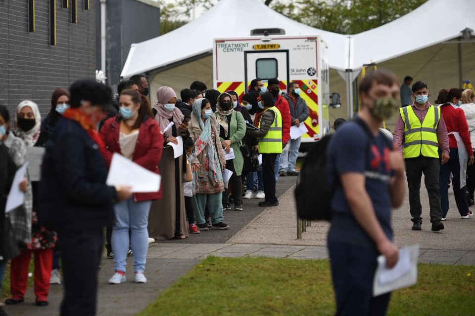 People at the Essa academy in Bolton queue at a temporary vaccination centre