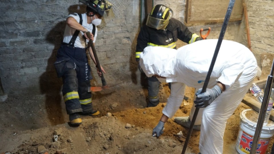 Police and firefighters dig in a basement beneath the suspect's home