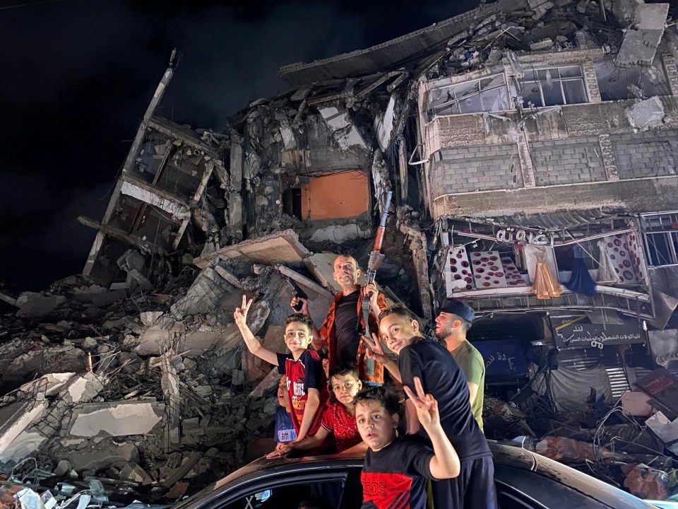 Locals pose in front of a home reduced to rubble