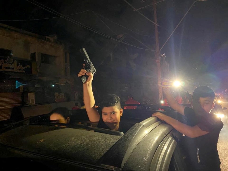 Boys pose with guns as Palestinians celebrate in the streets following the ceasefire