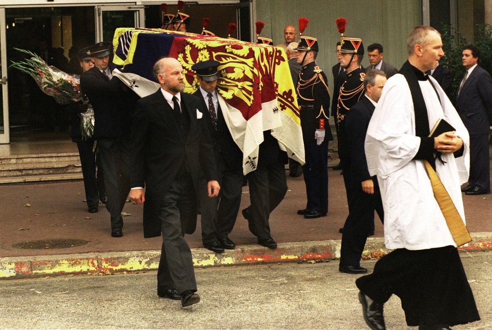 Guards stand at attention as pall bearers carry the Royal Standard-covered coffin of Diana