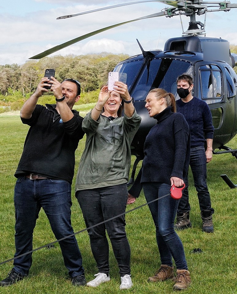 Tom keeps social distance as he poses with fans in front of a helicopter during filming