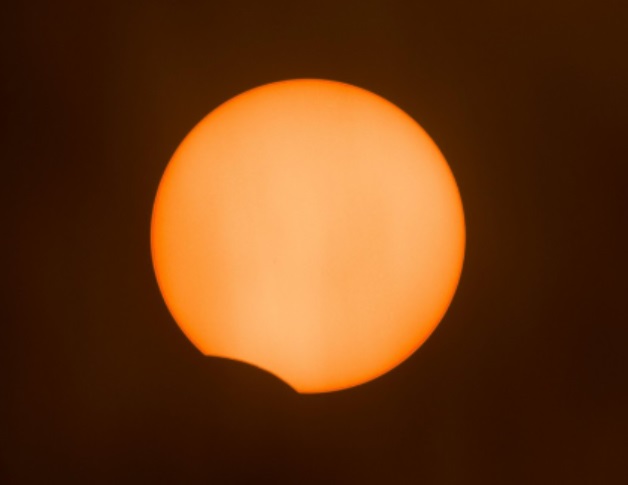 Partial solar eclipse begins, seen through thick patchy cloud above London CREDIT: Alamy